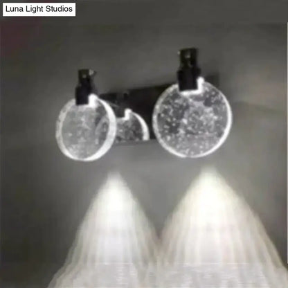 A modern gold crystal led wall lamp with three simple crystal led circular globes and black fixtures emitting white glow