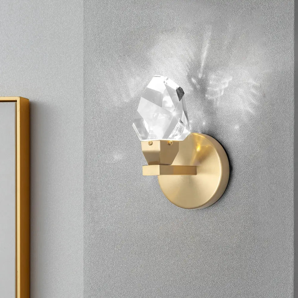A modern gold-toned crystal led wall sconce with a clear faceted pendant for luxury bedroom decor by decorbites crystal led