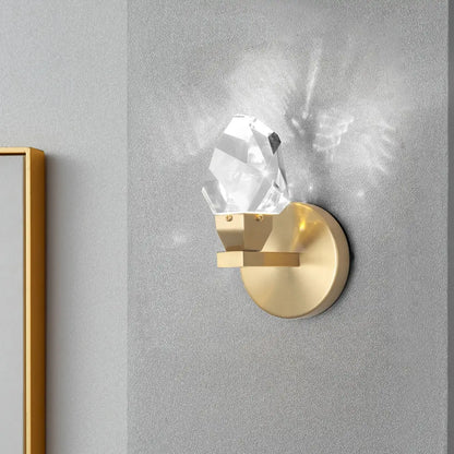 A modern gold-toned crystal led wall sconce with a clear faceted pendant for luxury bedroom decor by decorbites crystal led