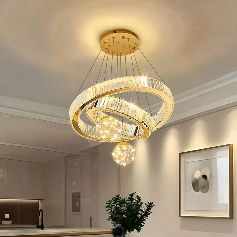 Modern gold pendant light with two interlocking crystal rings and brushed stainless finish for dining room use