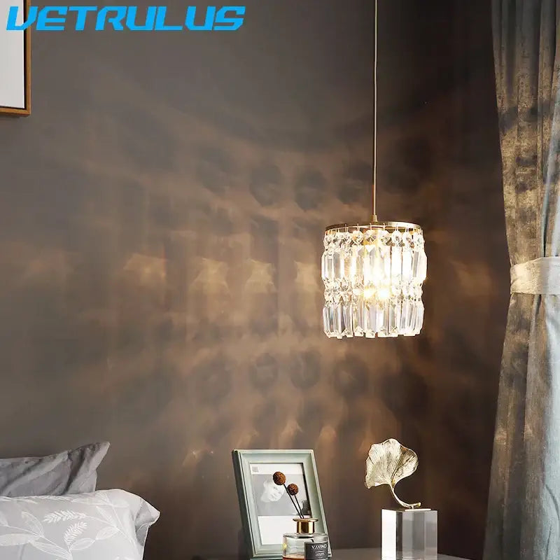 A modern gold crystal pendant light chandelier with a delicate cylindrical crystal design for dining rooms