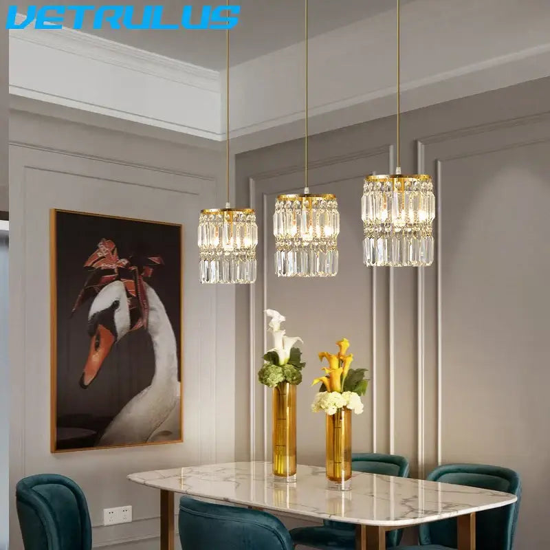 Three elegant gold crystal pendant lights with cascading glass prisms for modern dining room chandelier lighting