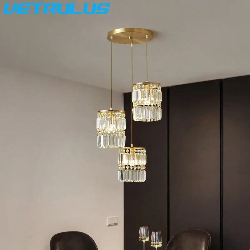 Modern gold crystal pendant light with three cascading tiers of faceted glass elements for dining room chandelier