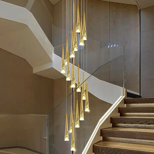 Modern gold crystal pendant light with sleek tapered glass shades hanging in a staircase setting for elegant lighting