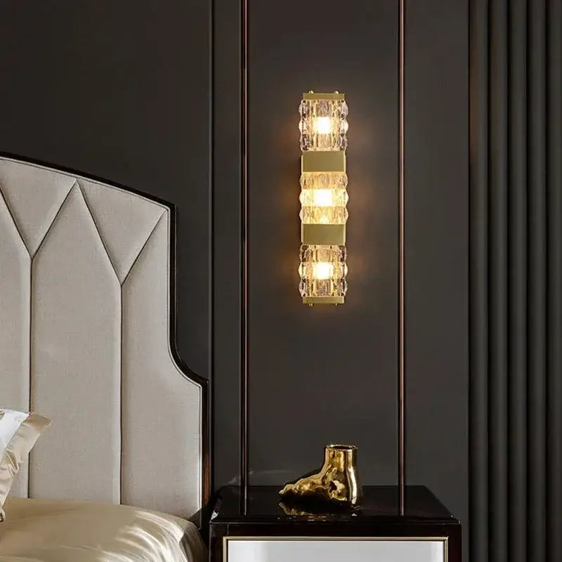 Modern gold crystal rectangle wall lamp with vertical design featuring gold metal and clear crystal segments emitting warm light