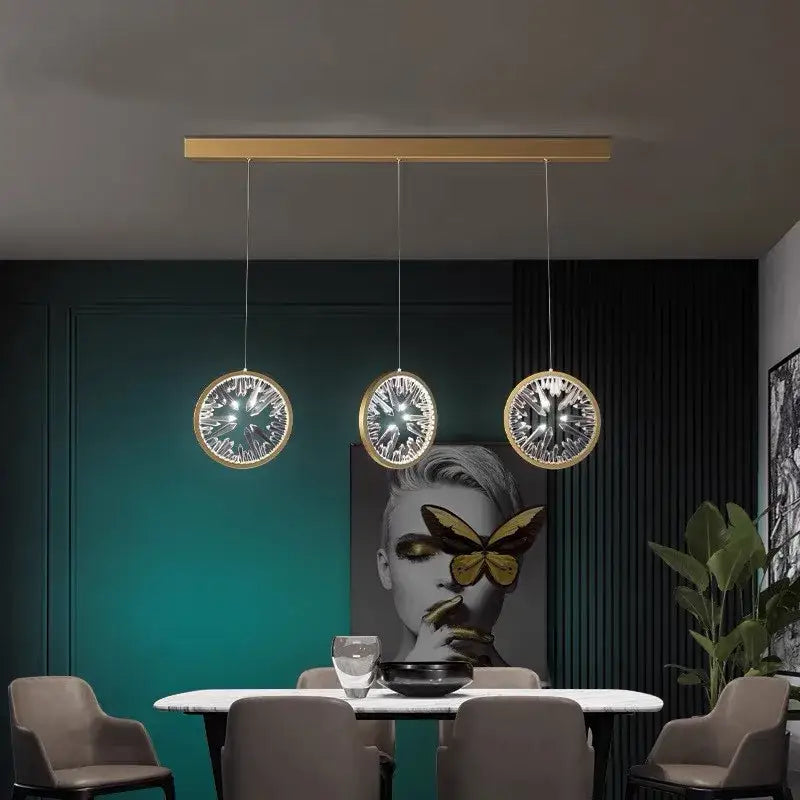 Three modern gold crystal ring led pendant lights with intricate glass patterns hang on a sleek horizontal bar