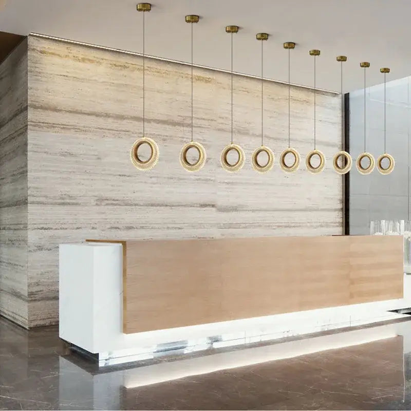 Modern gold crystal ring led chandelier with warm golden finish pendant lights above reception desk decorbites crystal ring