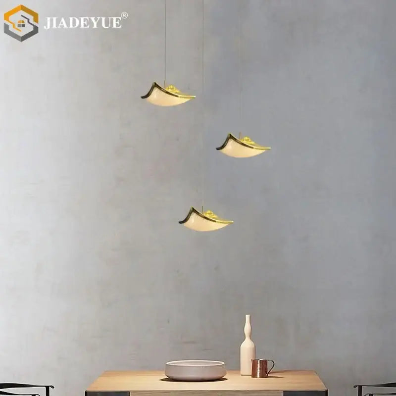 Three elegant gold-accented pendant lights with curved white shades enhance a modern decorbites crystal sand staircase chandelier dining room light