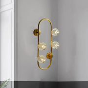 Modern gold wall lamp with five faceted crystal shade globes on a curved frame direct wired electric fixture