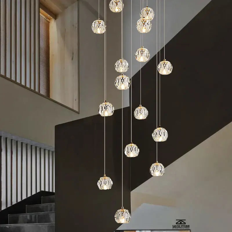Modern gold crystal stair football shaped chandelier featuring faceted glass orbs with gold metallic bases suspended by thin cords