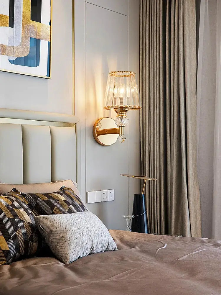Modern gold crystal wall lamp featuring a faceted tiered glass shade with crystal accents and a circular mirrored base