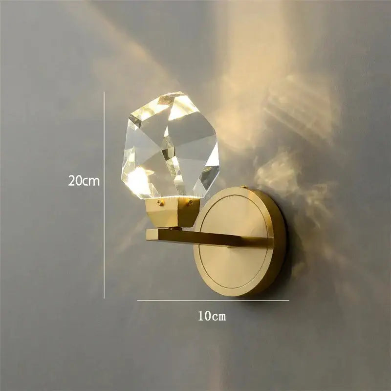 Modern gold crystal wall lamp featuring a faceted clear globe and polished brass base for elegant bedroom decorbites crystal wall lighting
