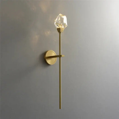 A sleek modern gold crystal wall lamp with a slender brass stem and faceted crystal bulb for elegant decorbites crystal wall decor