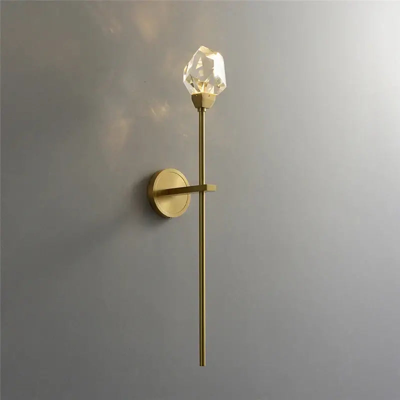 A sleek modern gold crystal wall lamp with a slender brass stem and faceted crystal bulb for elegant decorbites crystal wall decor