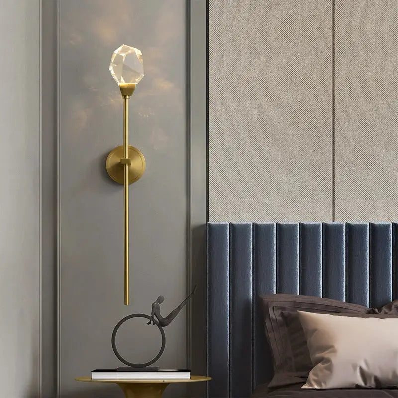 A sleek gold-toned modern crystal wall lamp with a faceted bulb and slender stem for elegant decorbites crystal wall decor
