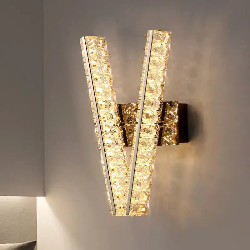 Modern gold wall lamp with v-shaped clear crystal strips in a sleek metallic frame for elegant living room decorbites crystal wall lighting