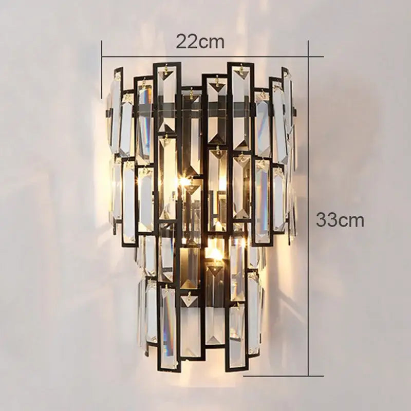A modern gold crystal wall lamp with black metal frame and cascading clear prisms creating warm light for living room
