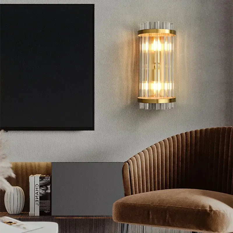 Modern gold crystal wall lamp featuring gold-toned cylindrical design with clear glass rods and warm glowing lights