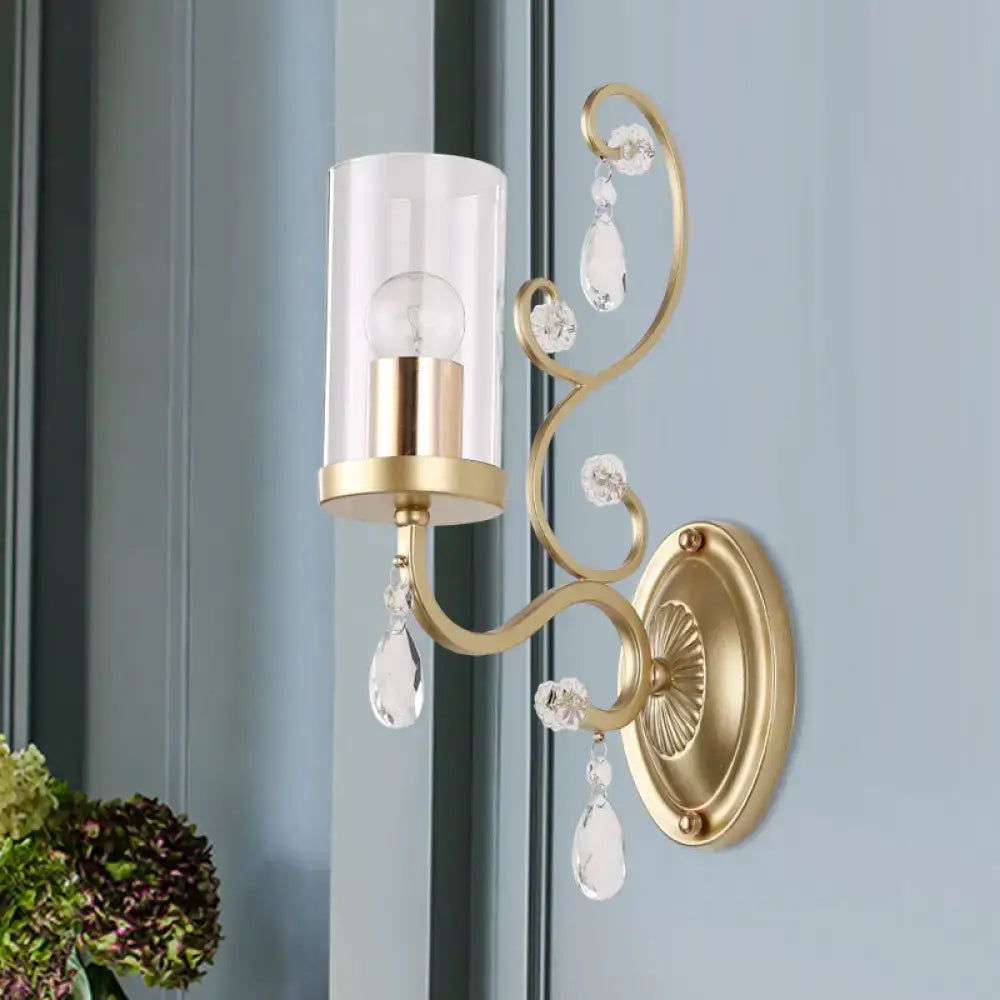 Modern gold wall light with clear glass cylinder shade and crystal droplets for elegant bedroom lighting