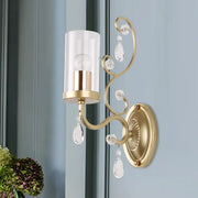 Modern gold wall light with clear glass cylinder shade and crystal droplets for elegant bedroom lighting