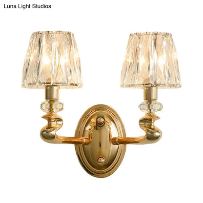 Modern gold wall light fixture with two crystal lampshades and ornate twisted arms for bedroom lighting