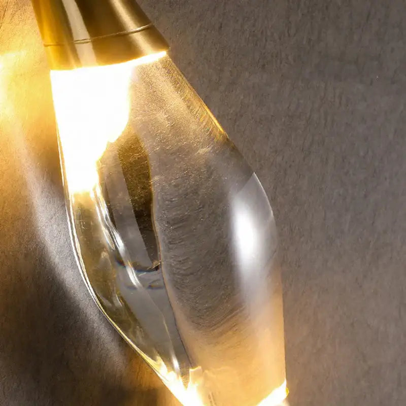 Modern gold crystal wall sconce with a golden metallic top and clear glass body emitting warm light for bedroom decorbites crystal wall decor