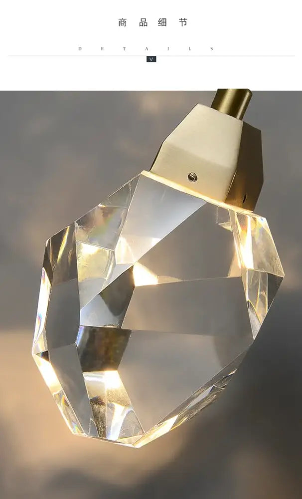Modern gold crystal wall sconce light with faceted crystal pendant and gold-toned metal cap designed to refract light