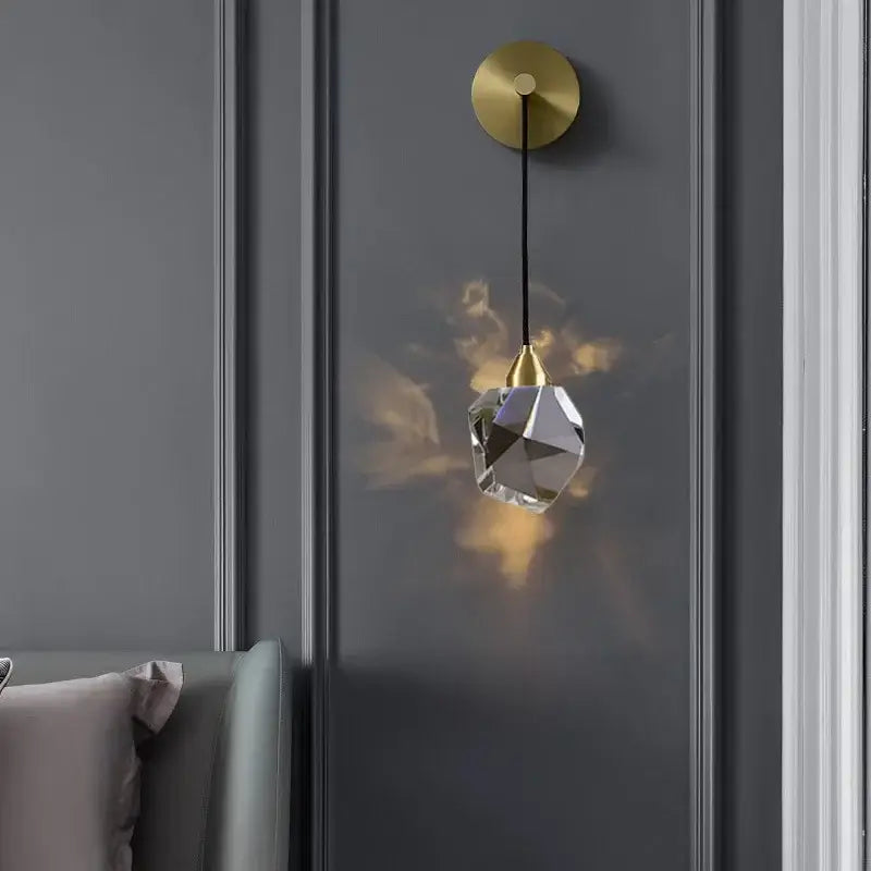 Modern gold crystal wall sconce light with irregular faceted glass shade and warm ambient illumination for living room