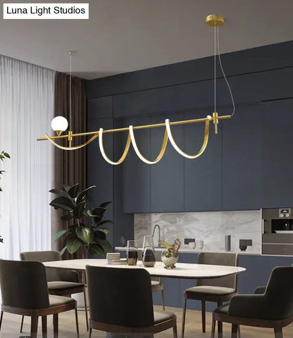 Gold-toned modern curve island light with sleek design and integrated glass ball bulb as kitchen island light fixture