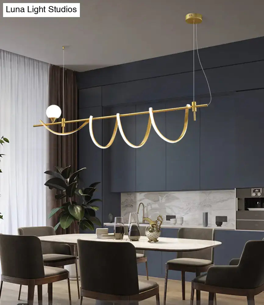 Gold-toned modern curve island light with sleek design and integrated glass ball bulb as kitchen island light fixture