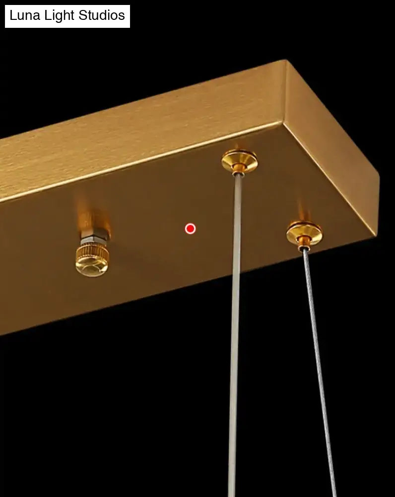 Modern gold curved crystal chandelier with gold-finished rectangular ceiling fixture and brass fittings as suspended crystal chandelier