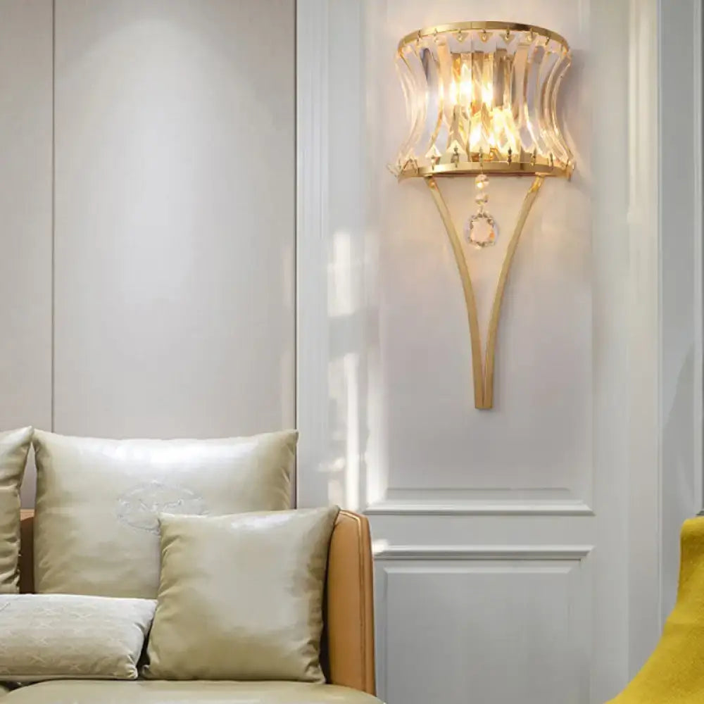 Modern gold curved wall light featuring a gold-toned sconce with clear crystal prism and fluted crystal shade for bedroom