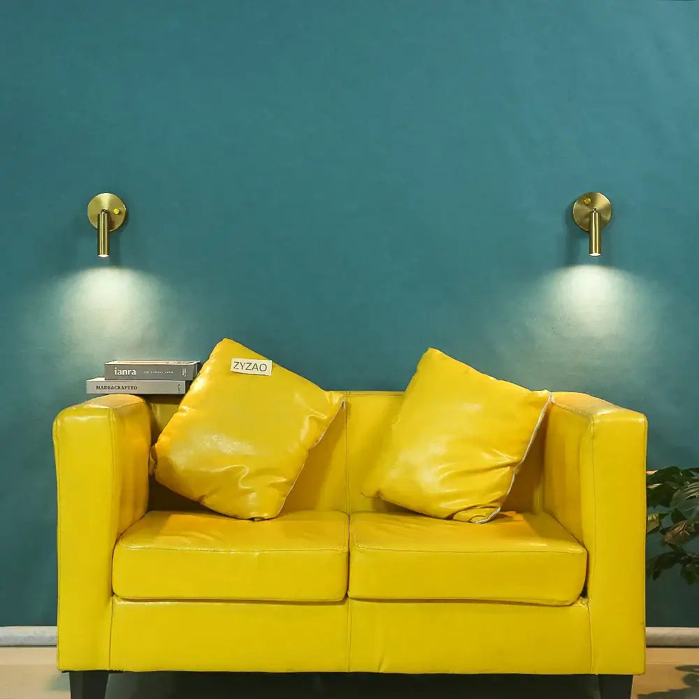Bright yellow leather sofa with matching cushions under modern gold cylindrical led wall lamp with knob switch