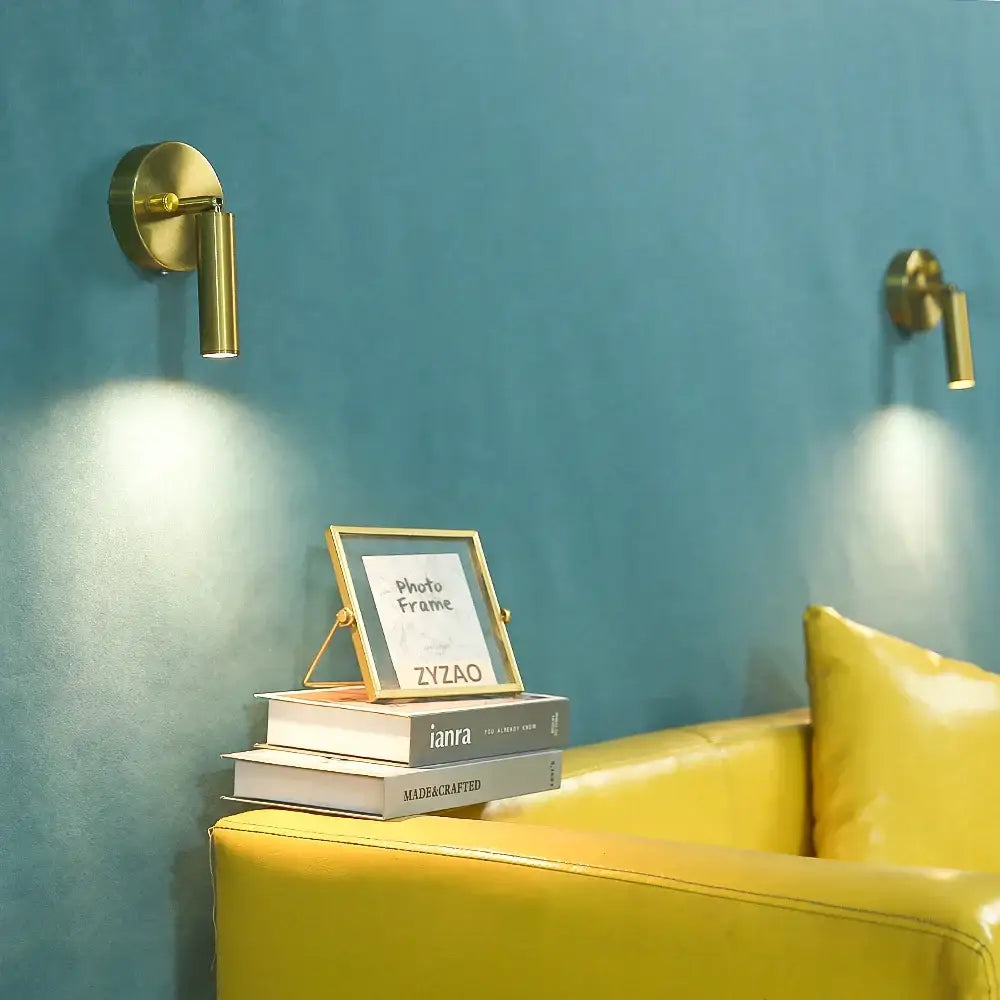 Gold-framed photo frame on books beside modern gold cylindrical led wall lamp with knob switch for bedroom decorbites led wall lamp