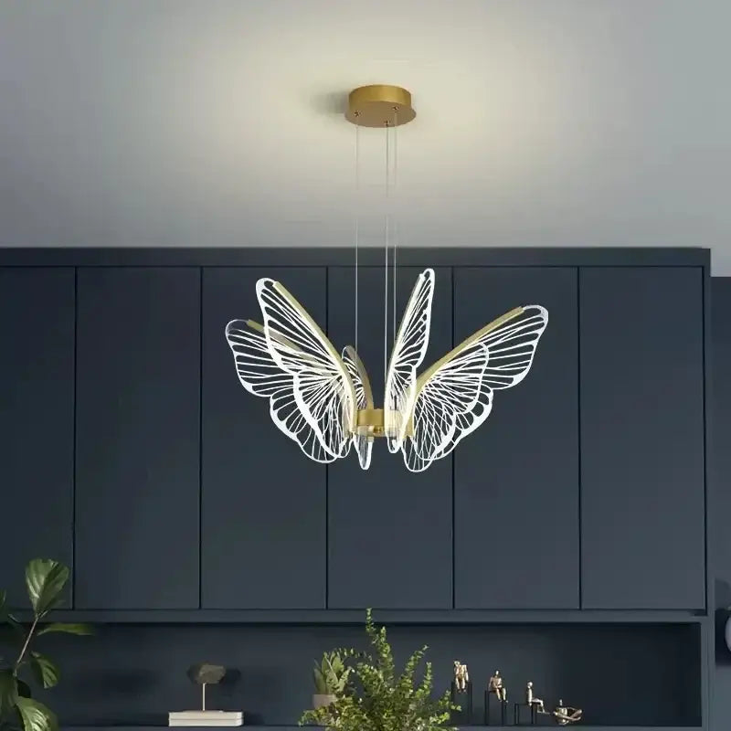 Modern gold decorbites butterfly pendant light with intricate white wireframe wings for dining room lighting