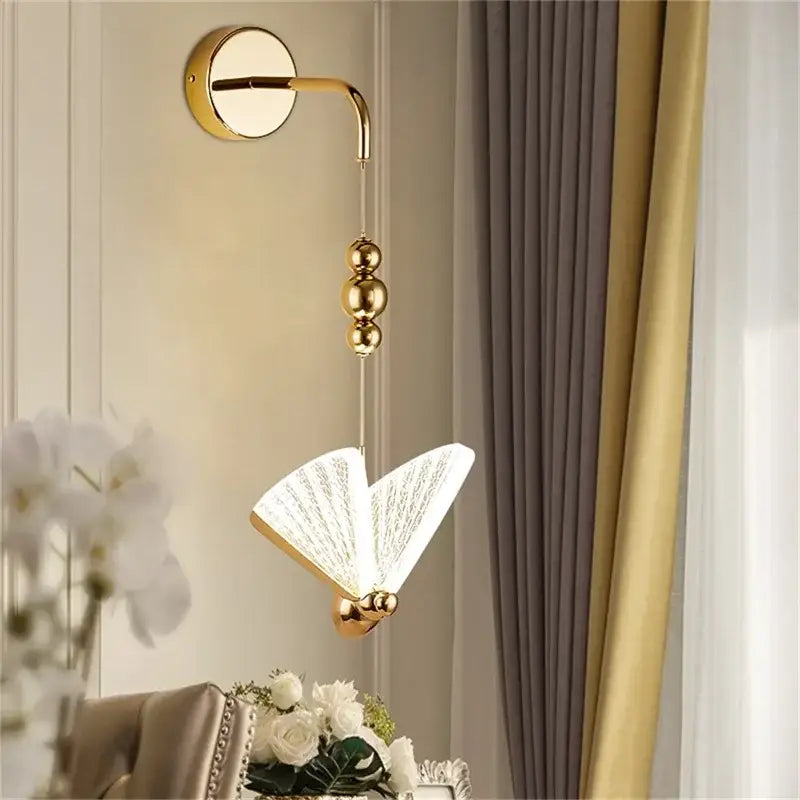 Modern gold decorbites butterfly wall light features a gold-finished sconce with an open-book glass lampshade for bedrooms
