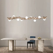 Modern gold decorbites caterpillar metal ball pendant light with polished spheres and white bulbs above marble table