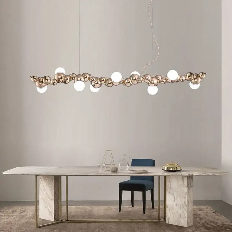 Modern gold decorbites caterpillar metal ball pendant light with polished spheres and white bulbs above marble table