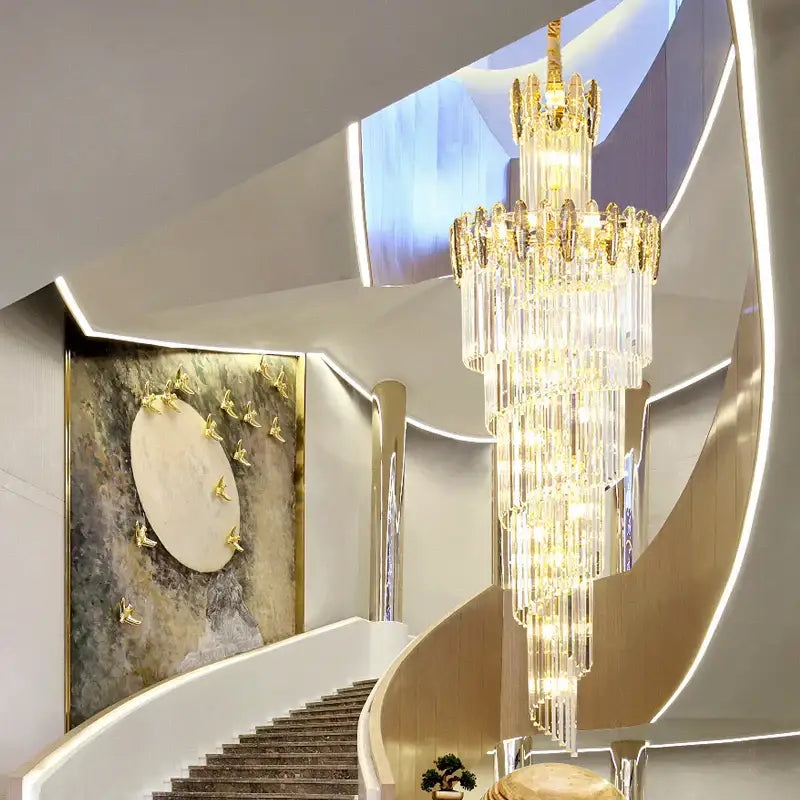 Modern gold decorbites crystal chandelier with cascading prisms hangs above a curved staircase in living room