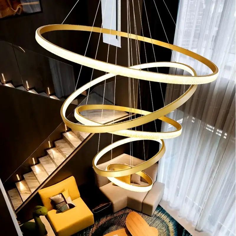 Modern gold decorbites crystal chandelier with multiple glowing rings suspended by thin cords for staircase lighting