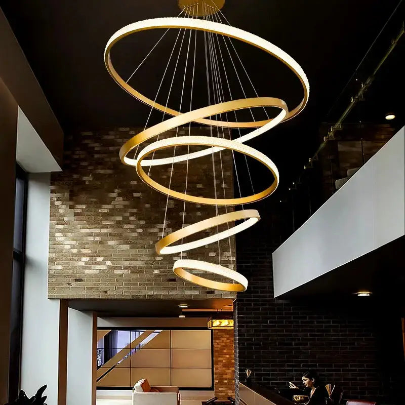 Modern gold decorbites crystal chandelier with multiple concentric rings suspended by thin cables for staircase lighting