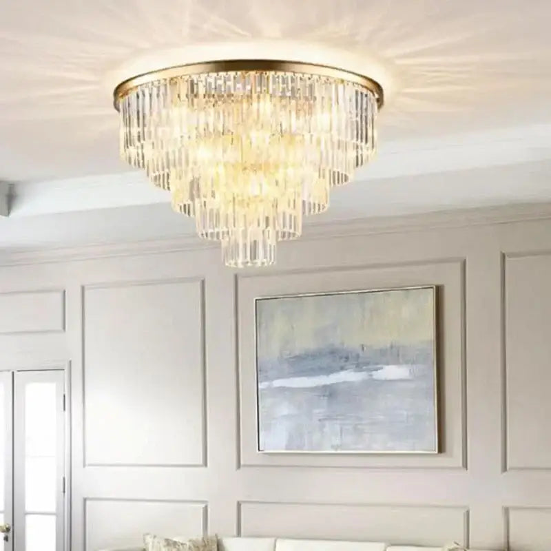 A tiered crystal flush ceiling light with a gold-toned metal frame and clear glass prisms by decorbites