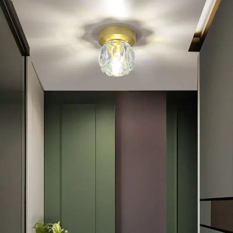 A modern gold decorbites crystal led ceiling light featuring a clear faceted crystal globe pendant with a gold base