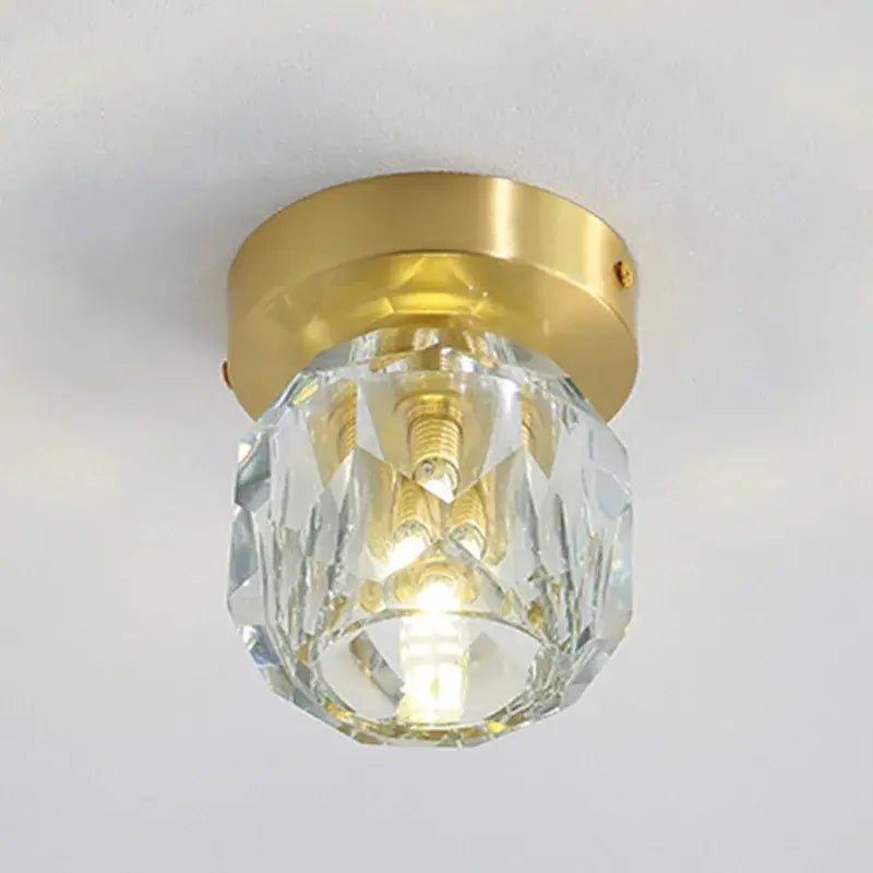 A clear faceted crystal globe with a gold metal base in a modern gold decorbites crystal led ceiling light