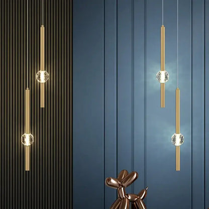 Modern gold decorbites crystal led chandelier featuring gold-toned cylindrical pendants with clear crystal spheres