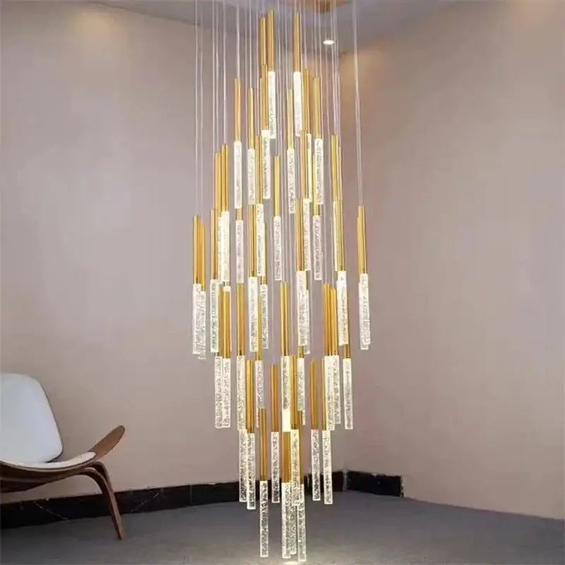 A modern gold decorbites crystal led chandelier with clear bubble-filled acrylic tubes glowing warmly in living room stairs