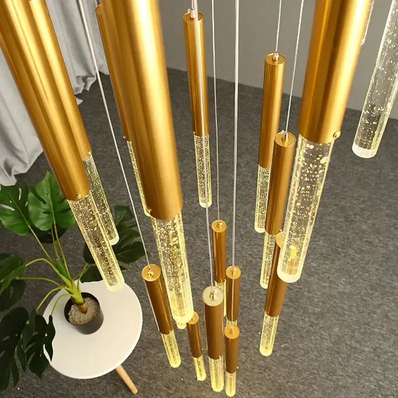 Modern gold decorbites crystal staircase chandelier with cylindrical pendant lights featuring glowing bubble-filled glass sections
