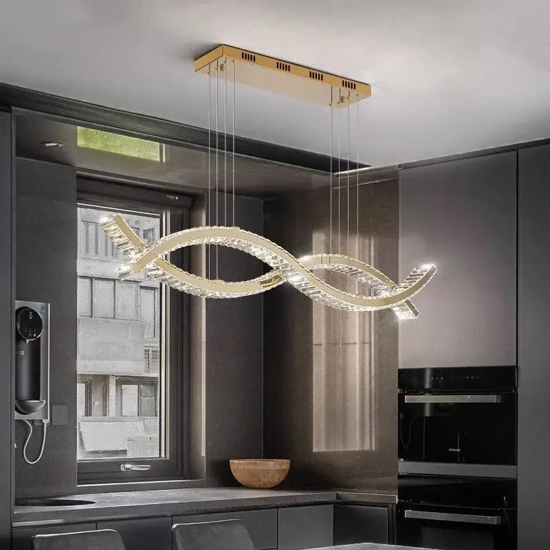 A modern gold-toned decorbites crystal strip chandelier with intertwined design and clear crystal accents for dining rooms