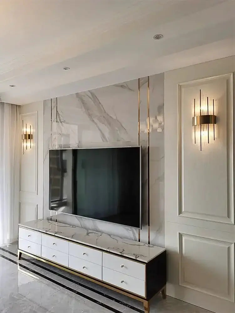 A sleek modern tv console with white marble top black sides and gold trim paired with a decorbites crystal wall lamp