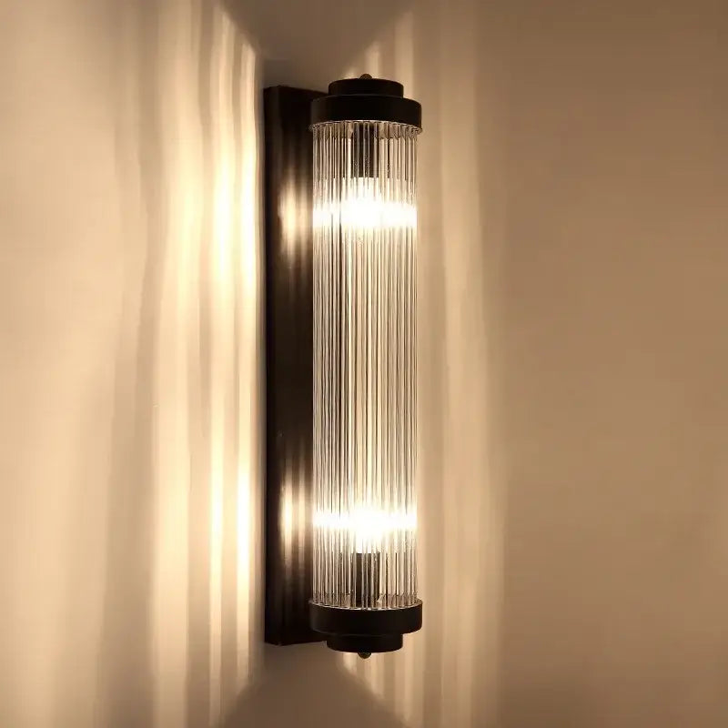 Modern gold decorbites crystal wall sconce with sleek black metal frame and glass rods diffusing warm light for bedroom